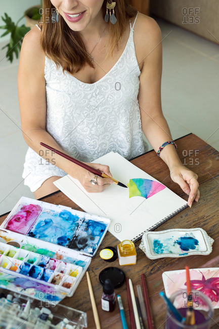 Latin artist painting with watercolor in her studio