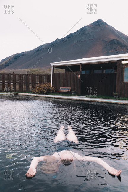 Woman resting in water of pool between dry lands