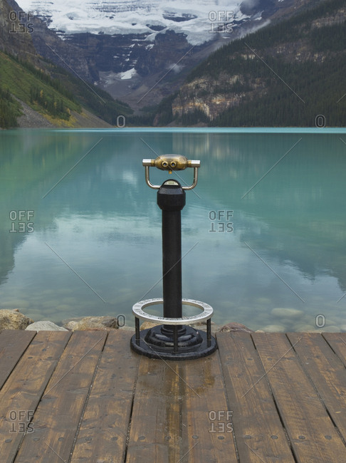 April 10, 2019: Binoculars overlooking still lake in rural landscape, Banff, Alberta, Canada