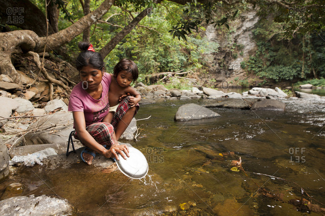 PHILIPPINES, Palawan, Barangay region,  - February 7, 2011: young Batak mother Diovina and daughter Lenilyn wash dishes in the stream in Kalakwasan Village