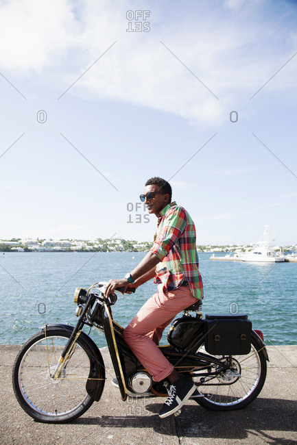 BERMUDA, Hamilton. - September 12, 2015:  Chef Marcus Samuelsson on a vintage scooter in Barr's Bay Park located in downtown Hamilton. The Hamilton Harbour is in the background.