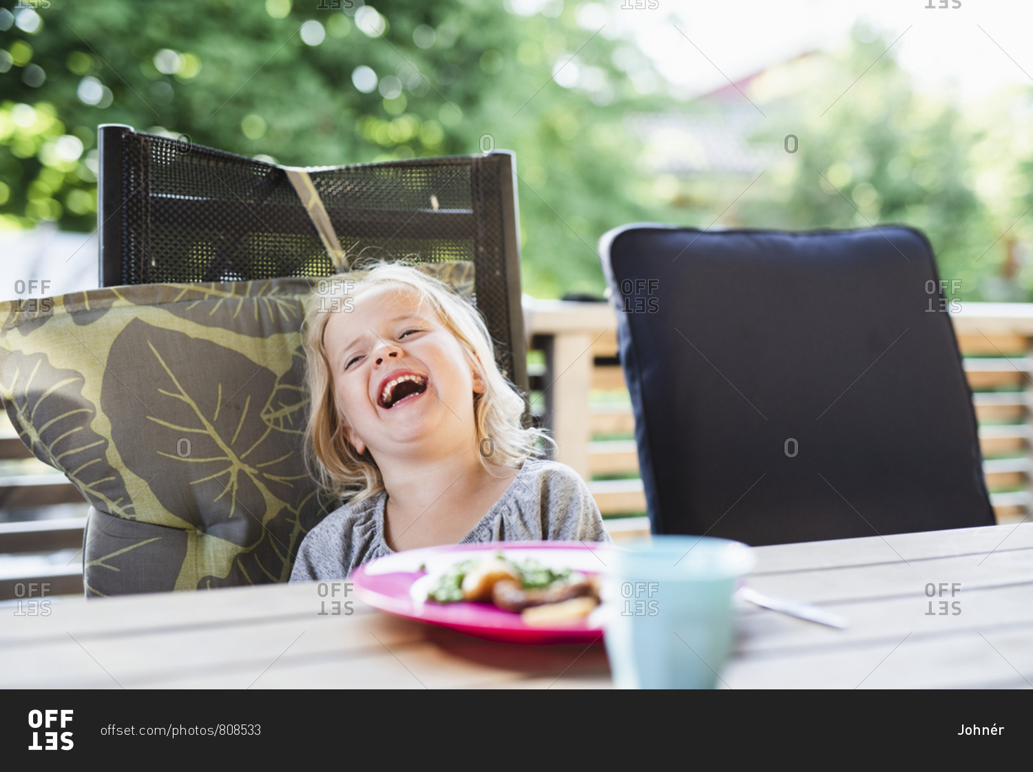 Laughing Girl At Table - Offset Stock Photo - Offset