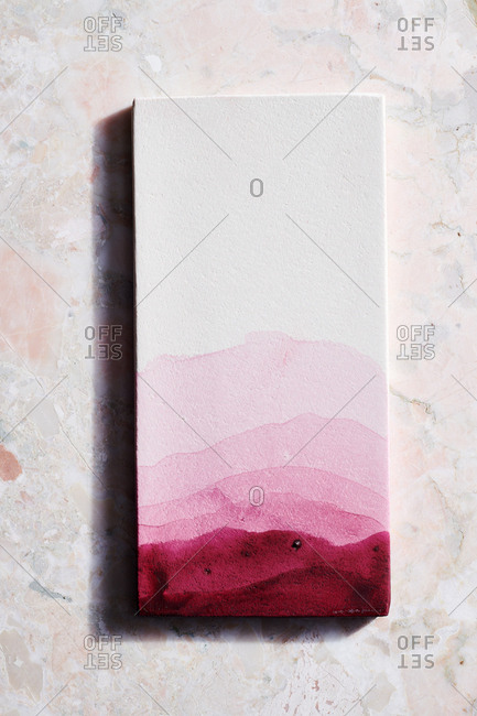 Magenta ombre of natural dye on a white rectangle and marble surface