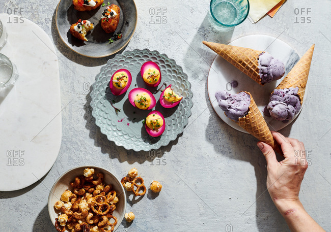 Hand reaching towards ice cream cone in a spread of elevated midwestern snacks