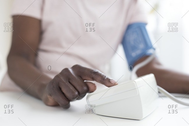 Mature woman testing blood pressure with machine.