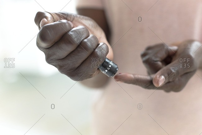 Mature woman testing blood glucose with finger prick test.
