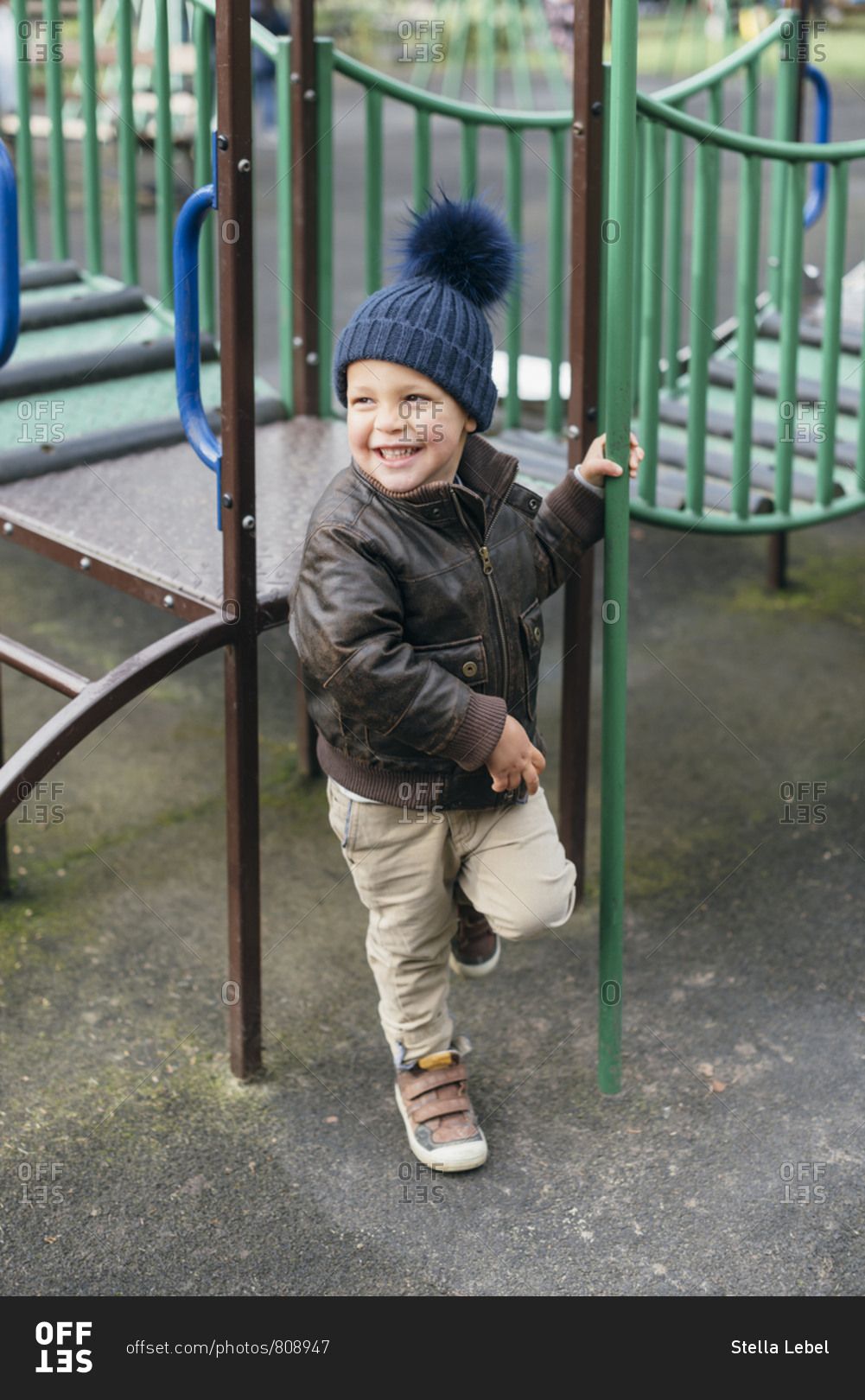 Happy young boy holds fireman\'s pole in playground