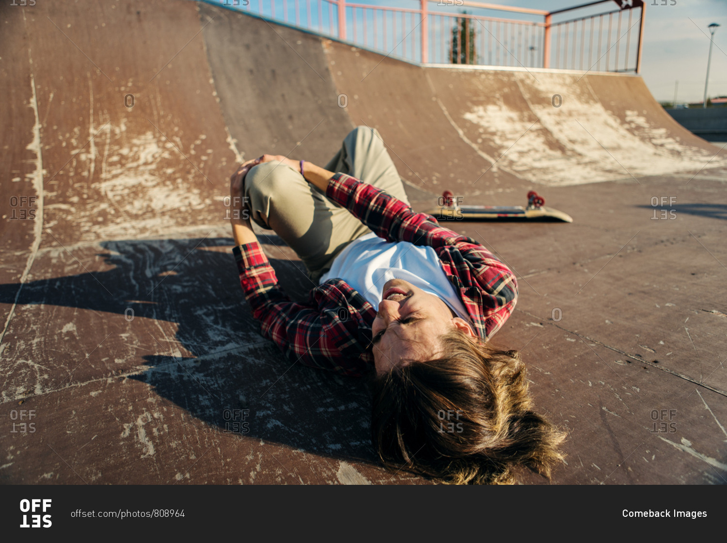 Young Skateboarder Lying On Back In Skatepark Ramp After Painful Fall ...