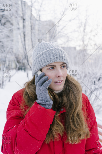 beautiful young woman laughing in red down jacket speaks by phone