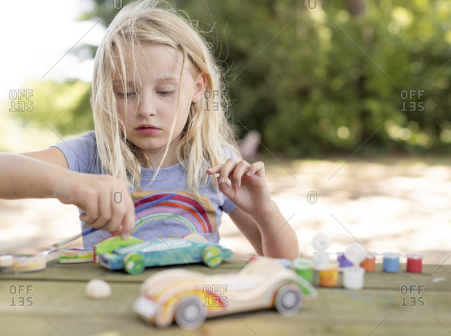 Girl painting a race car  with messy hair