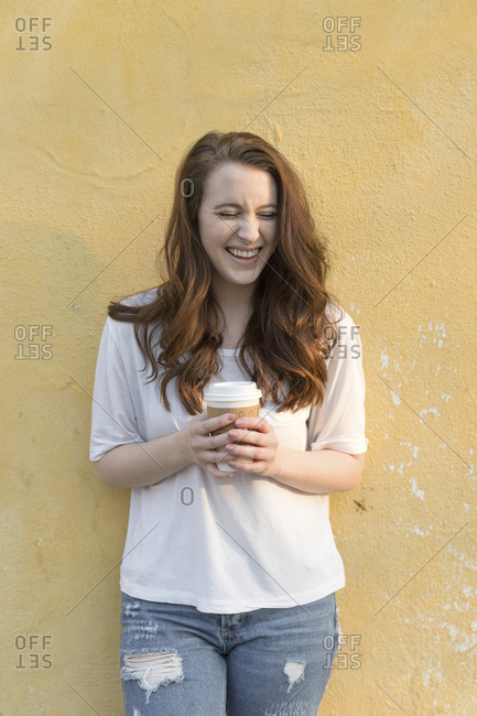 girl laughing with long brown hair holding coffe