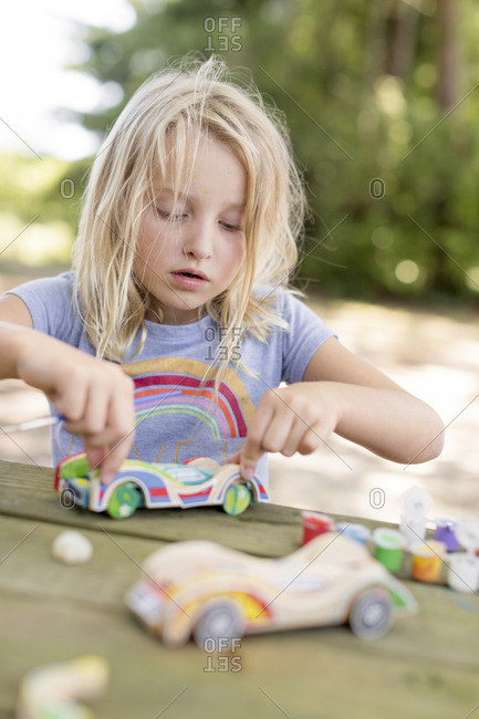 little girl with blonde hair doing arts and crafts outdoors