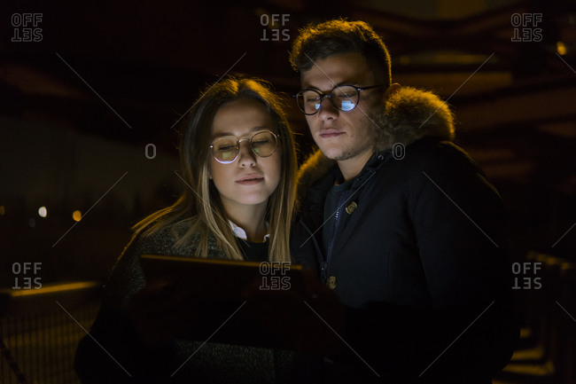 Serious White young couple on web using tablet device outside