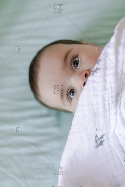 Close up of baby looking up and covered by blanket