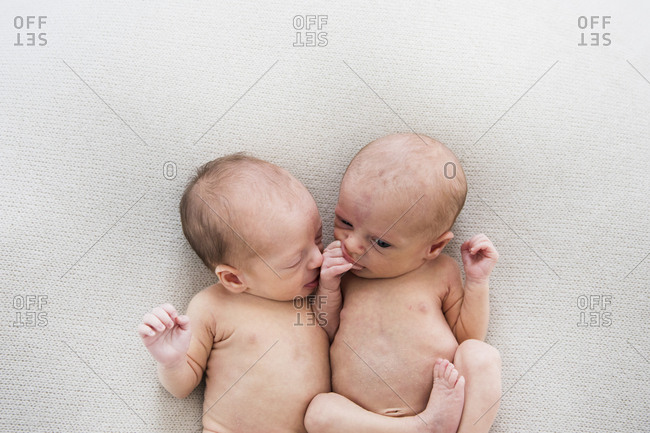 Fraternal Newborn Twins on a Off-White Blanket, Chewing Their Hands
