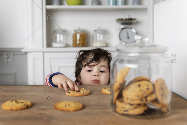 Young boy reaching at cookies on kitchen table