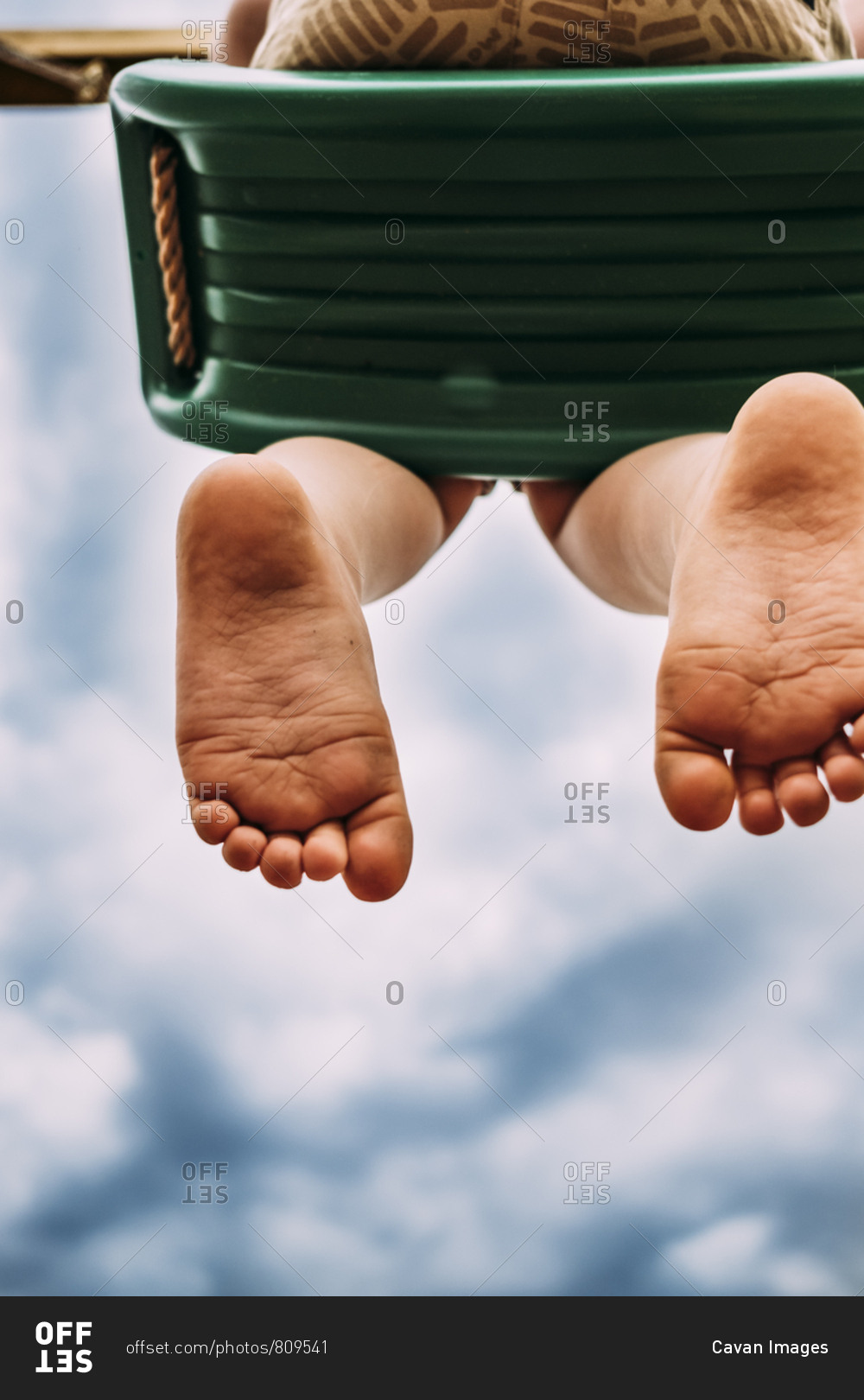 Young kid on swing with dirty feet stock photo OFFSET
