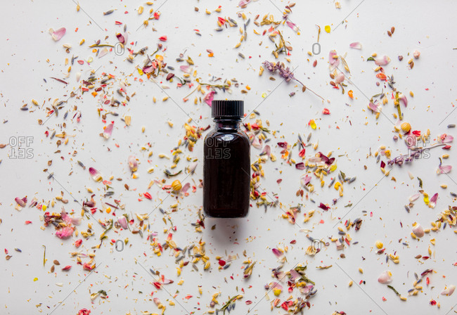 Black glass bottle with lavender flower petals on a white background