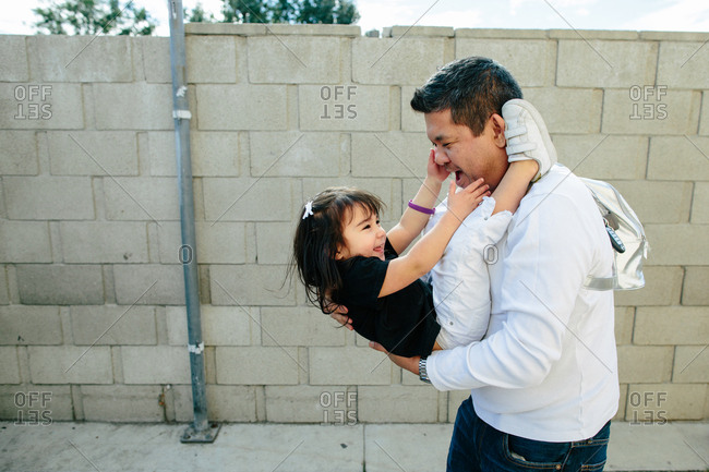 Father dips toddler daughter playfully