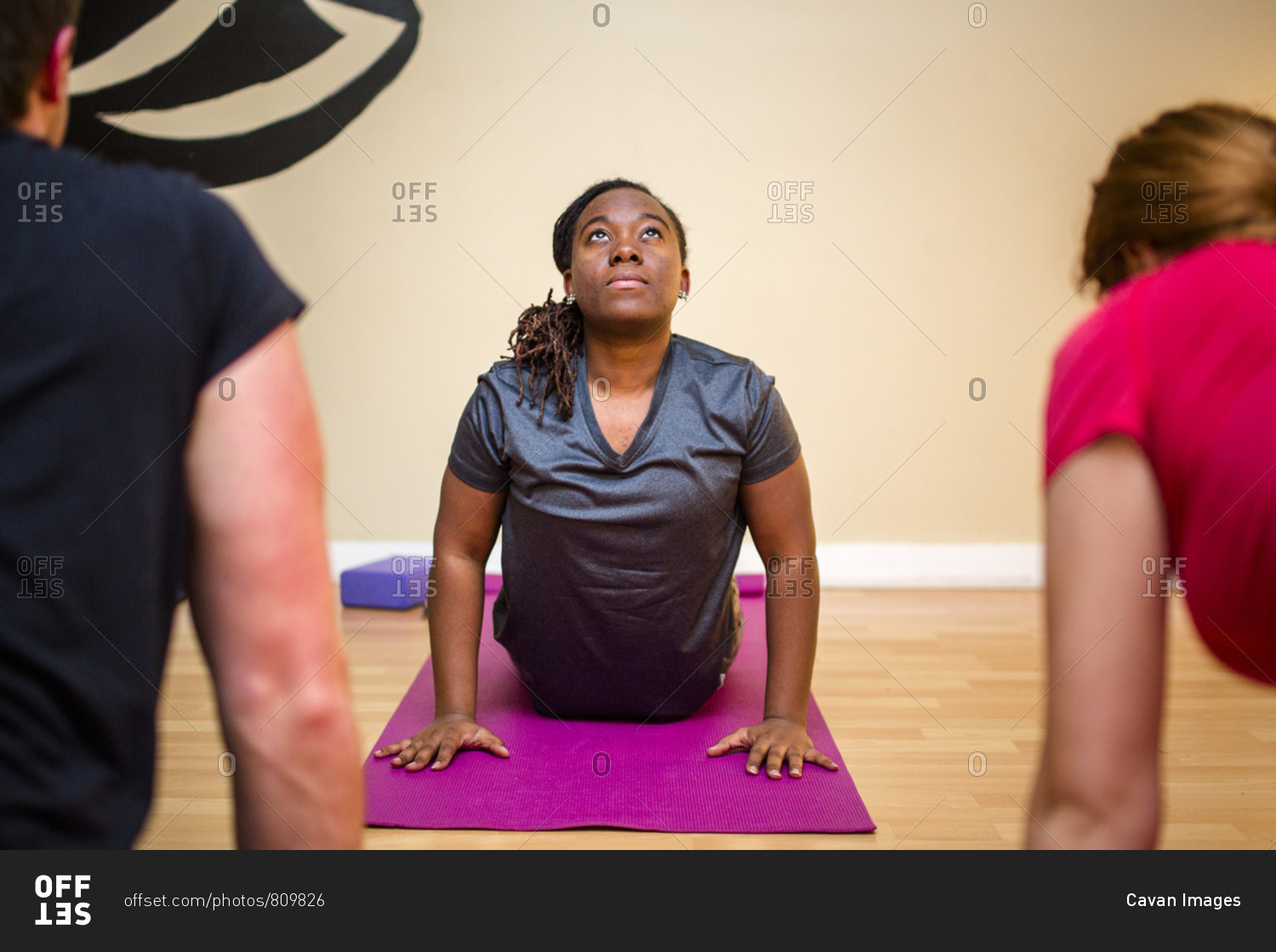 A woman arches back on an exercise mat with other yoga students