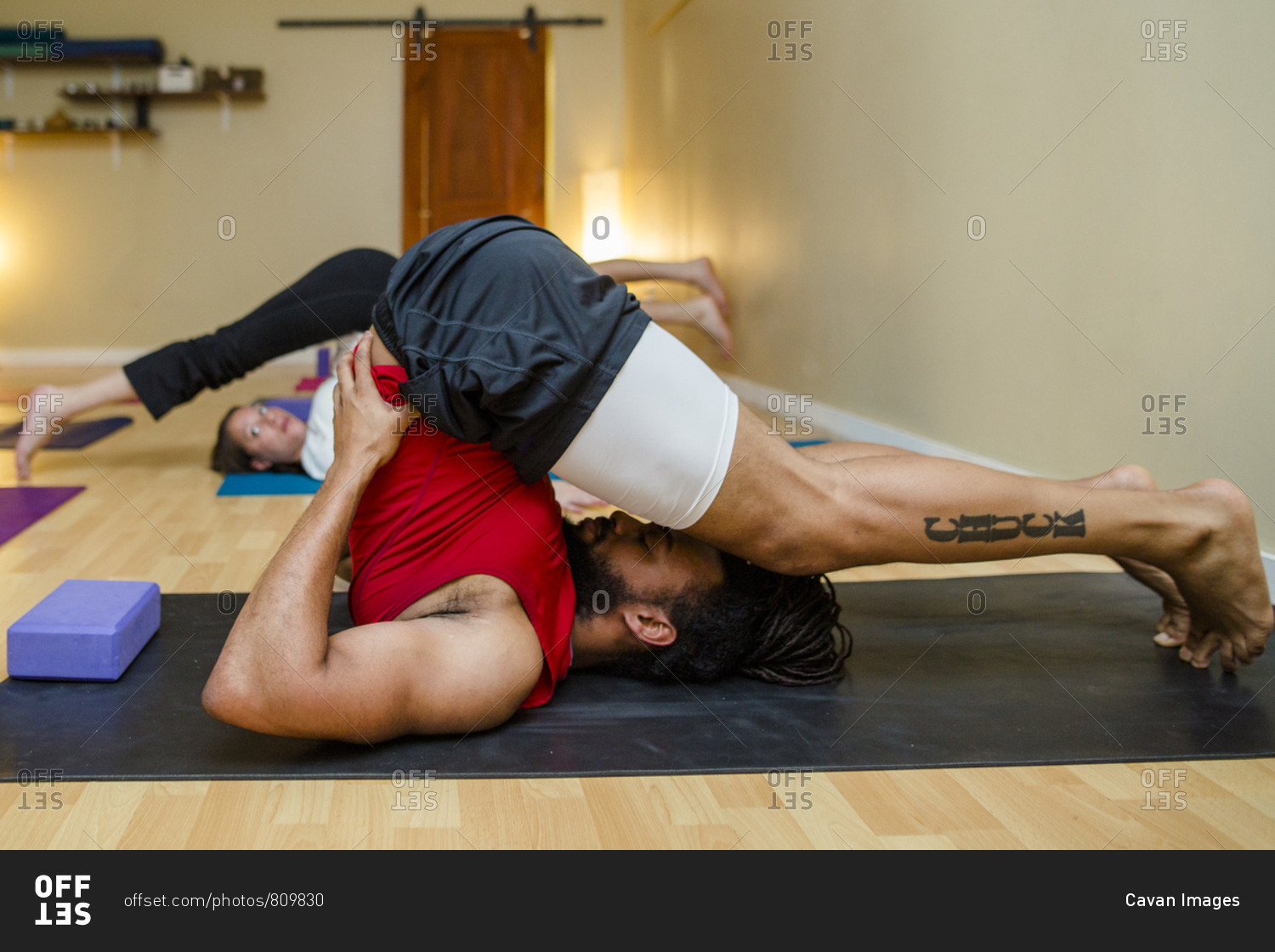 A man holds a yoga position in a yoga class