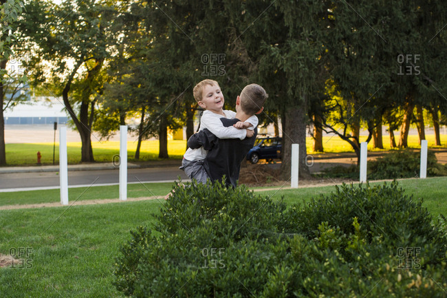 Two boys play together in front yard