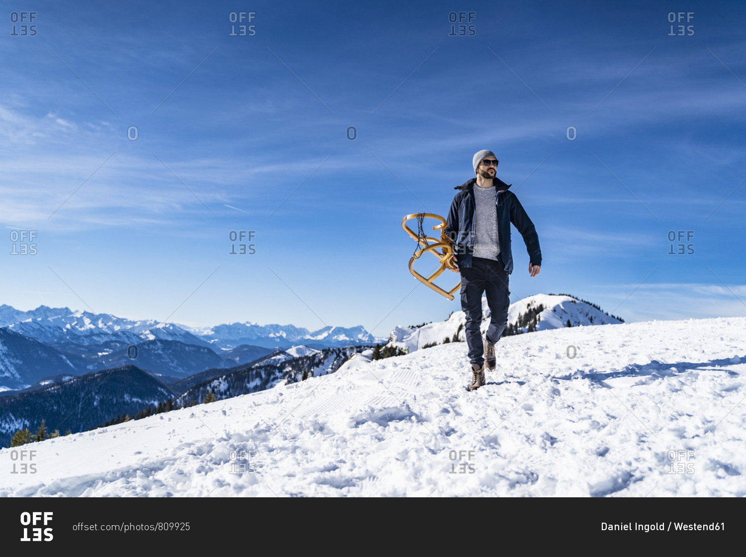 Germany- Bavaria- Brauneck- man carrying sledge in winter in the mountains