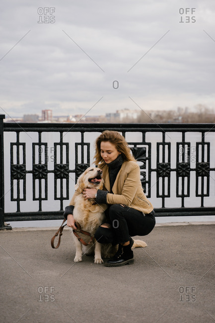 Beautiful blonde woman walking in the Park with a dog Golden Retriever walk in the city