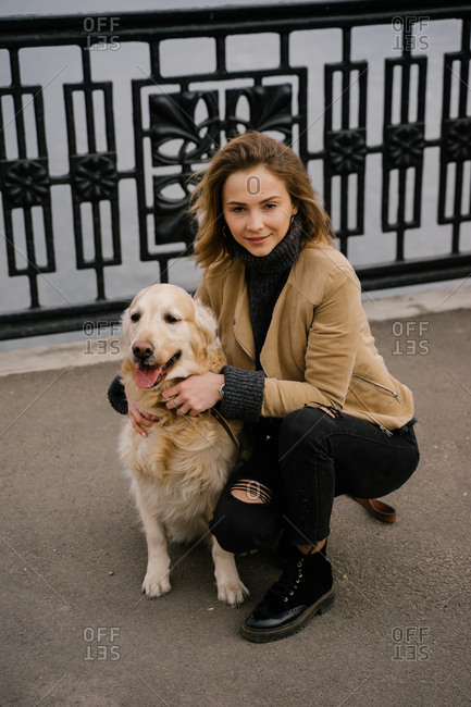 Beautiful blonde woman walking in the Park with a dog Golden Retriever walk in the city