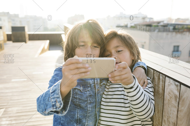 Two siblings taking a selfie with a smart phone on a rooftop