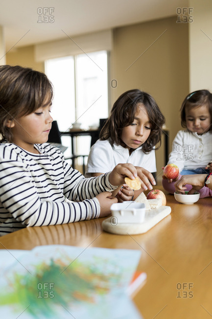 3 siblings  eating healthy snack at home in Barcelona