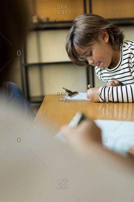 Little boy with striped top making a drawing at home