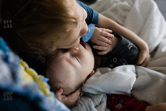 Toddler boy cuddling with his baby brother