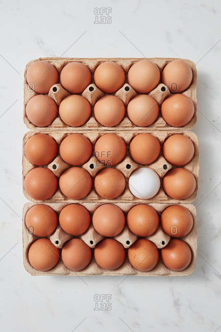 Brown and white chicken eggs in a carton box on a marble table with copy space as layout for your ideas. Easter concept. Flat lay