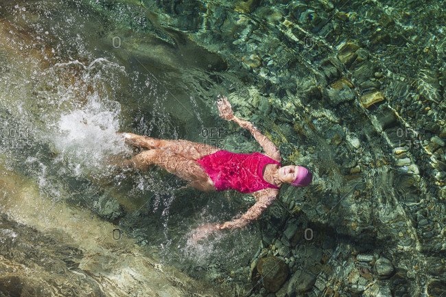 Switzerland- Ticino- Verzasca Valley- woman swimming in refreshing Verszasca river