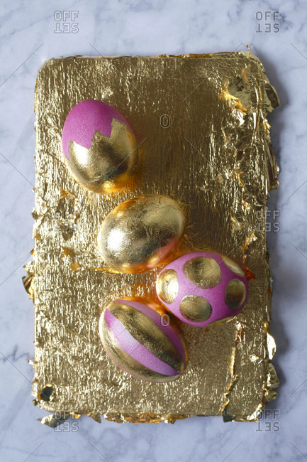 Four painted Easter eggs on golden background and marble