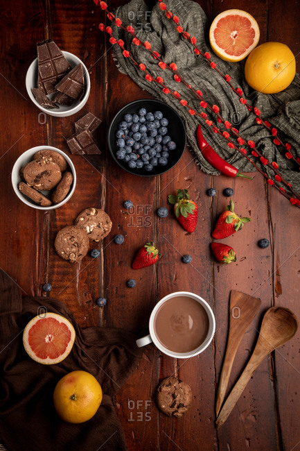Mug of tasty hot chocolate placed on timber tabletop near assorted desserts and fruits for breakfast