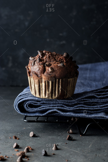 Yummy muffin made with chocolate and banana placed on blue towel near gray wall