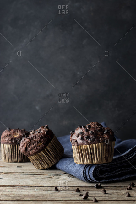 Yummy muffin made with chocolate and banana placed on blue towel near gray wall