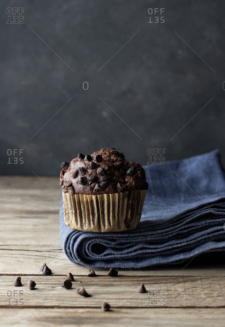 Yummy muffin made with chocolate and banana placed on blue towel near gray wall