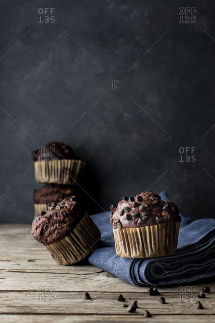 Yummy muffin made with chocolate and banana placed on blue towel near gray wall