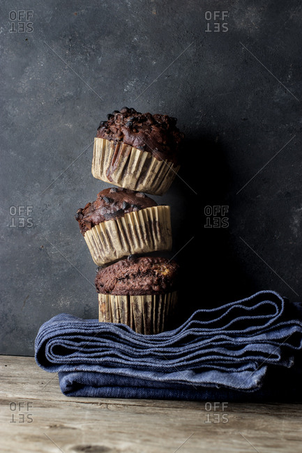 Yummy muffin made with chocolate and banana placed on blue towel near gray wall