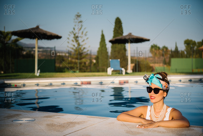 Young rich chinese woman sunbathing by a pool at a luxurious resort