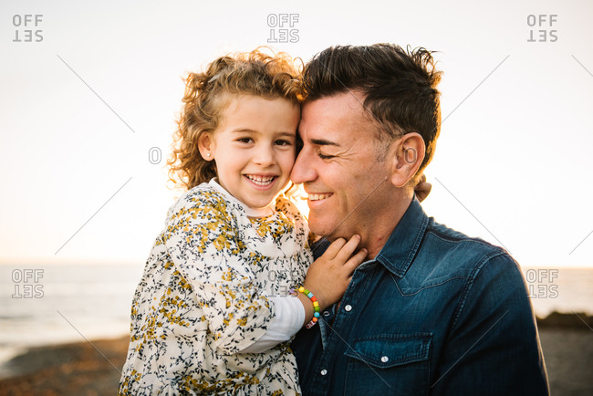 Middle aged man with her daughter at sea shore smiling and hugging each other
