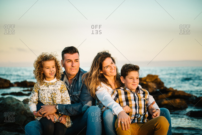 Middle aged man an woman with children at sea shore smiling and hugging each other