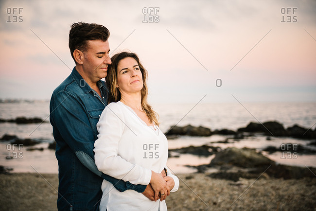 Middle aged man an woman hugging at sea shore and smiling