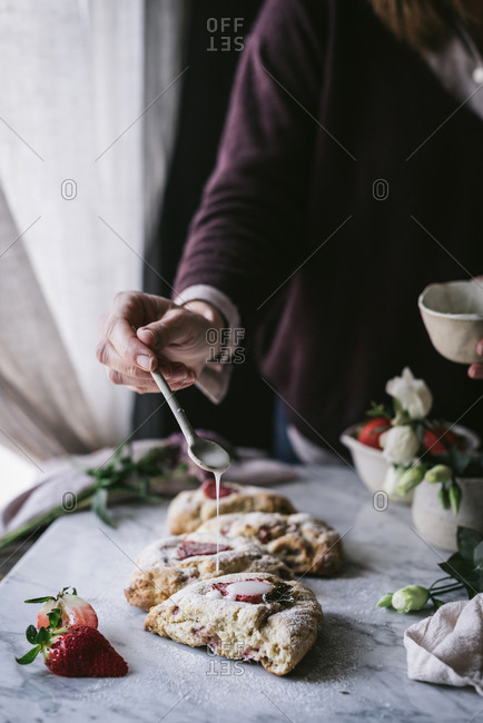 Crop person spilling sauce on scones