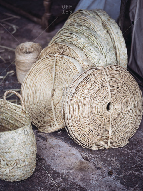 Set of rolls of woven dried palm fiber placed on floor in workshop