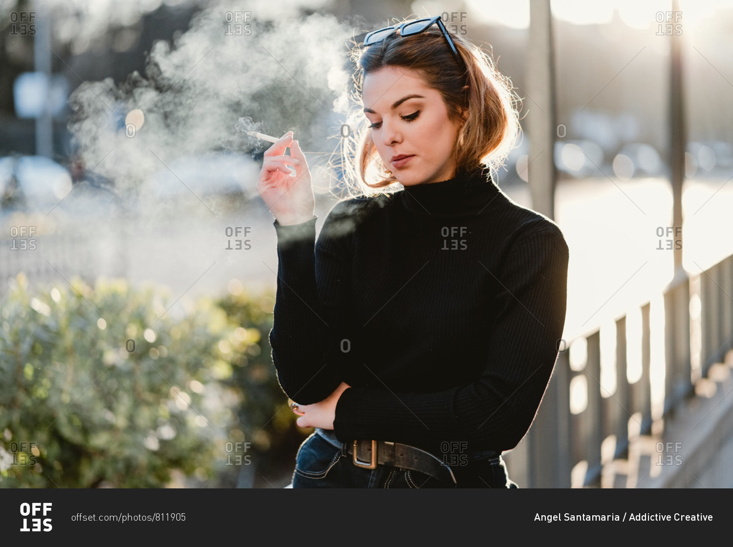 Beautiful lady in trendy outfit exhaling fume while smoking cigarette ...