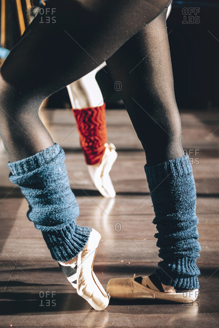 Crop side view of ballerina stretching and dancing in pointe shoes.